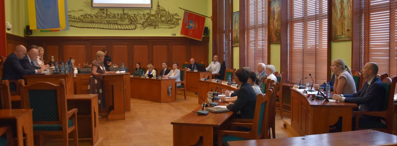 Grupa radnych na sali rycerskiej ratusza podczas sesji rady miejskiej