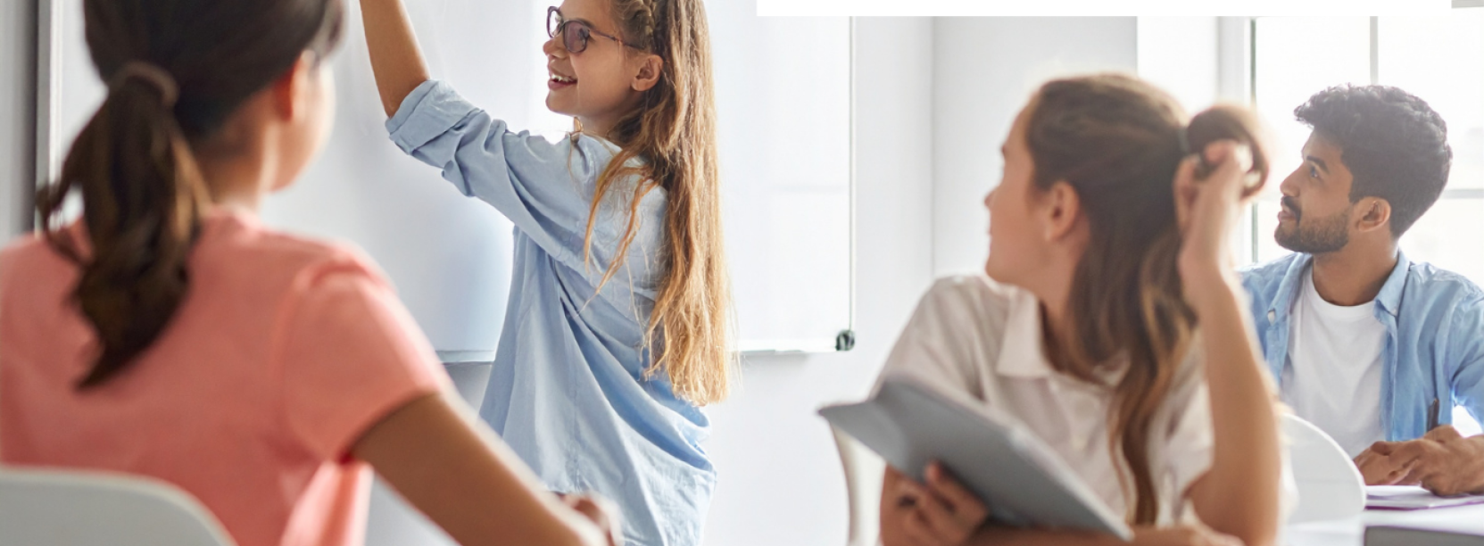 Grupa uczniów w klasie, jedna z uczennic pisze po tablicy