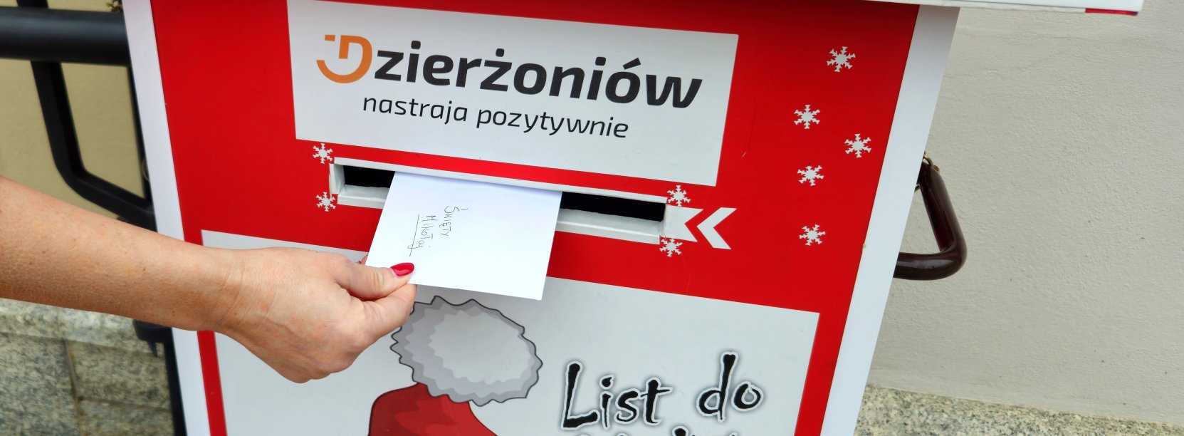 Zdjęcie skrzynki na listy do Mikołaja z ręką wrzucającą list