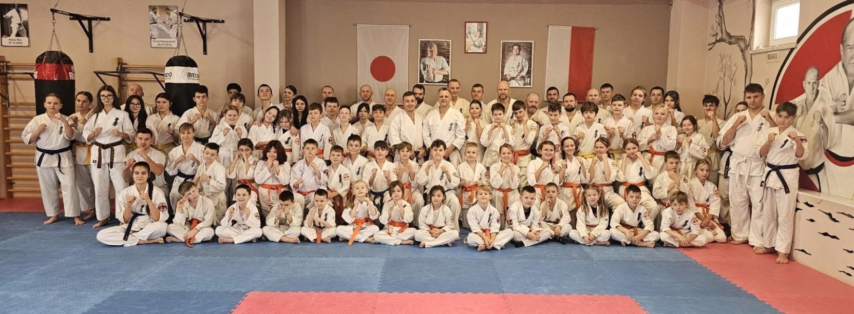 Duża grupa zawodników karate w kimonach na macie sportowej