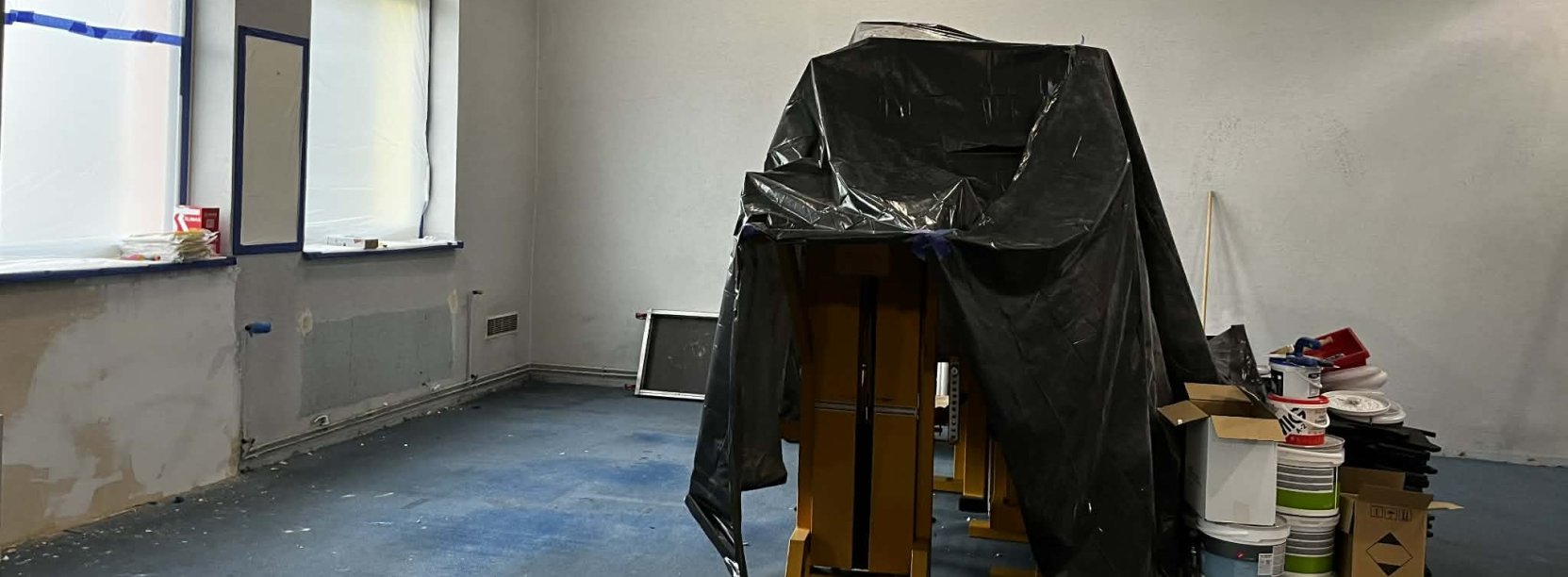 Pomieszczenie siłowni w remoncie, sprzęty zakryte folią malarską