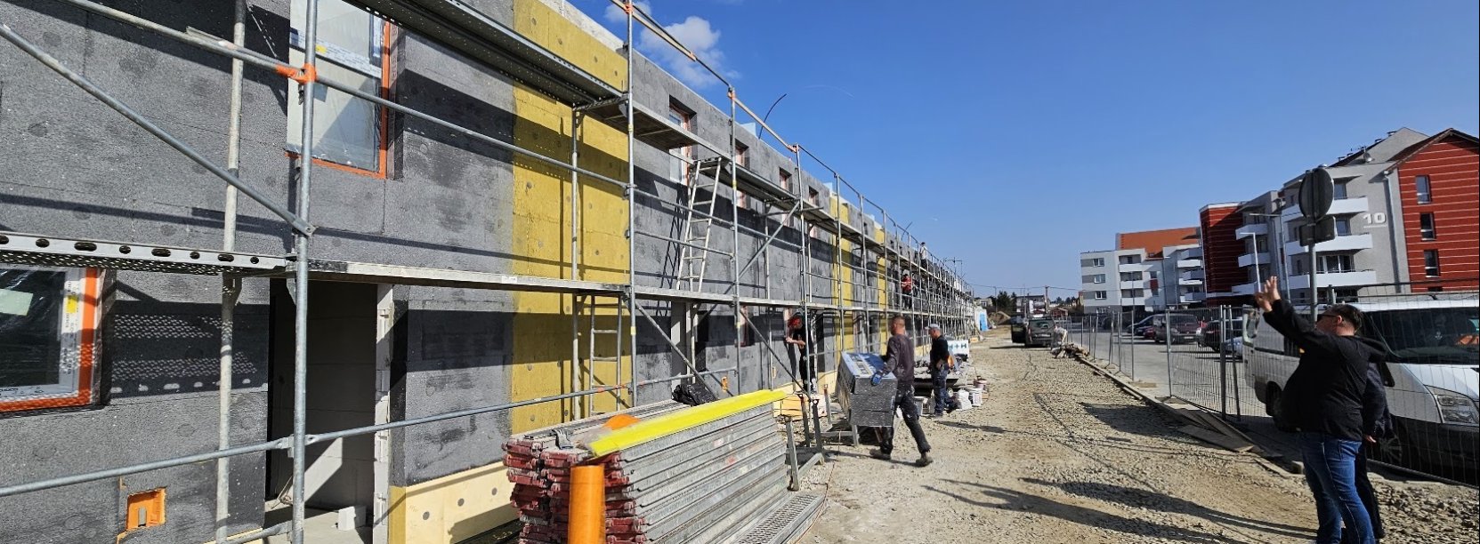 Budynek szeregowy w trakcie budowy, na drugim planie pracownicy przy rusztowaniu