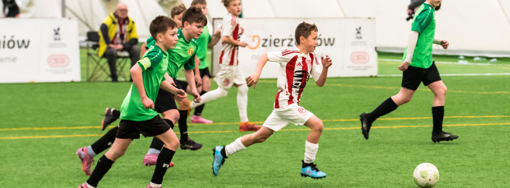 Młodzi piłkarze podczas meczu, obok sędzia