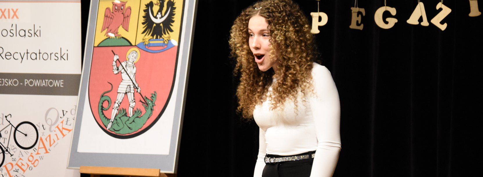 Dziewczyna w bałej bluzce i w kręconych włosachpodczas recytacji