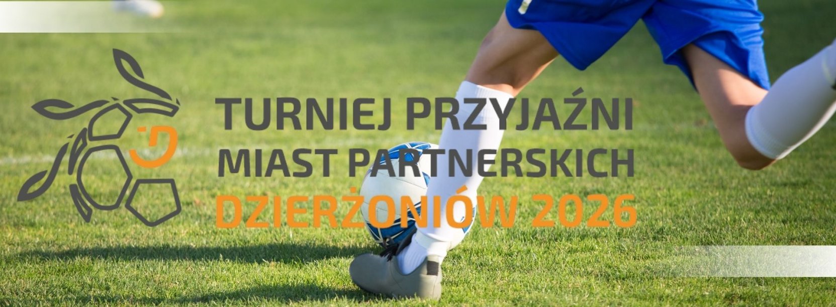 nogi piłkarza który kopie piłkę na boisku i napis turniej przyjaźni miast partnerskich