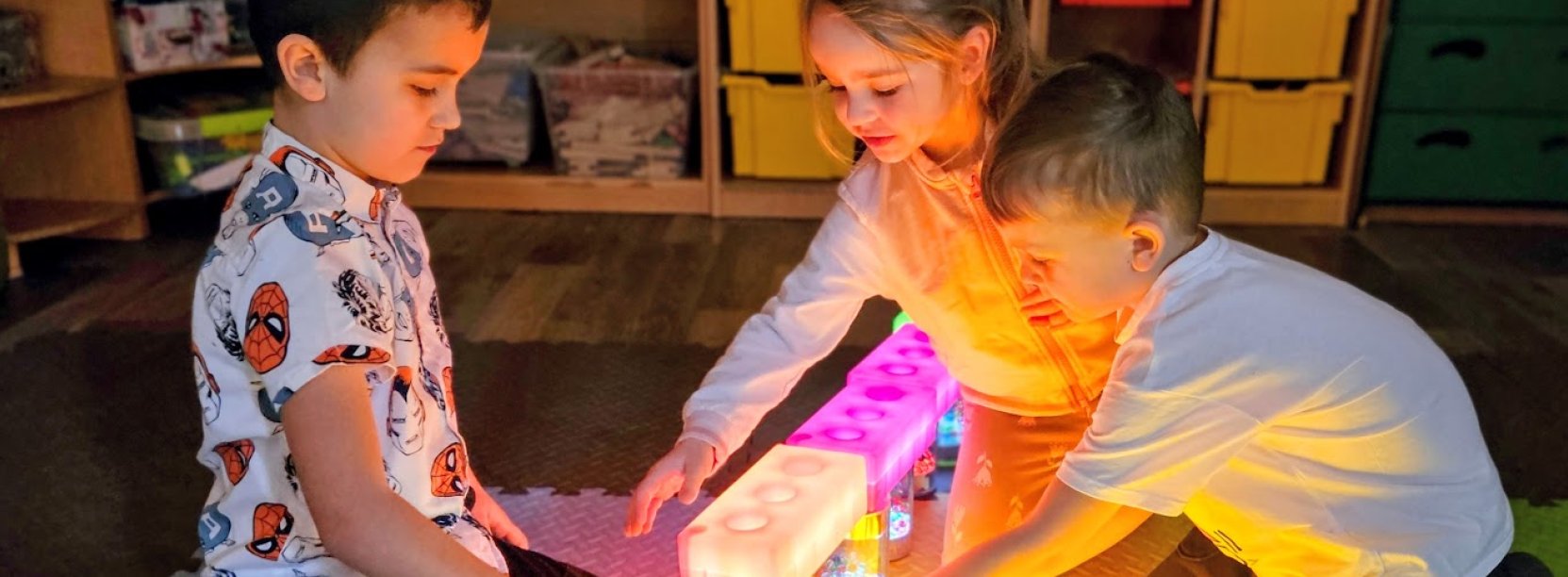troje dzieci bawiących się świecącymi klockami