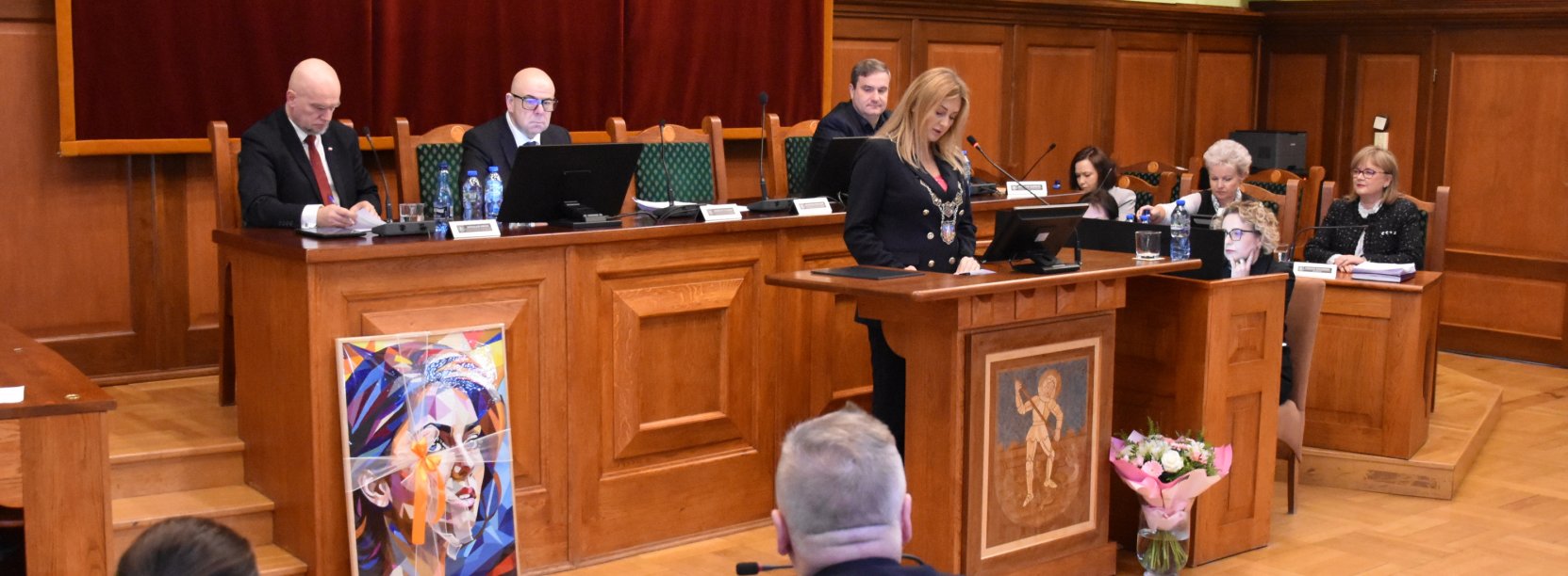 Sesja, przy mównicy przewodnicząca rady, za nią stół prezydialny i trzech wiceprzewodniczących