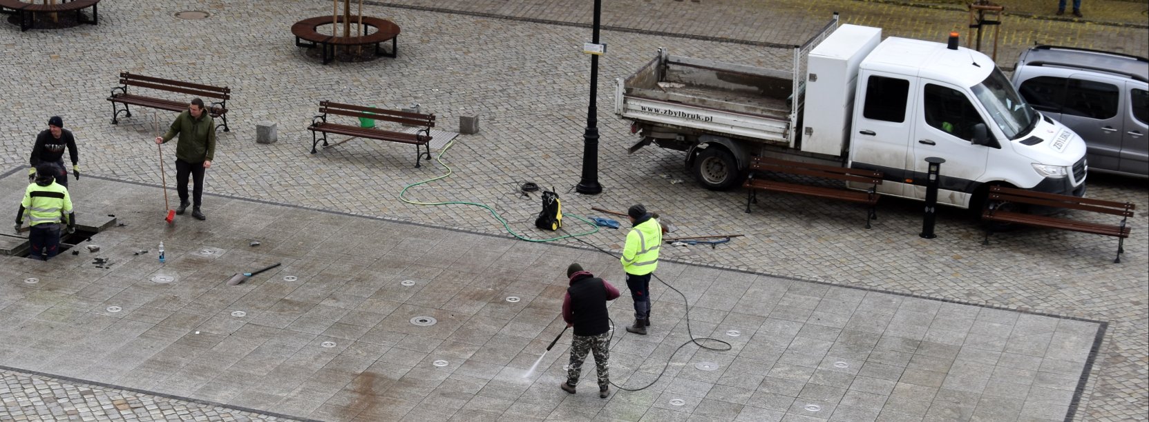 Pięciu pracowników czyści i sprawdza fontannę posadzkową