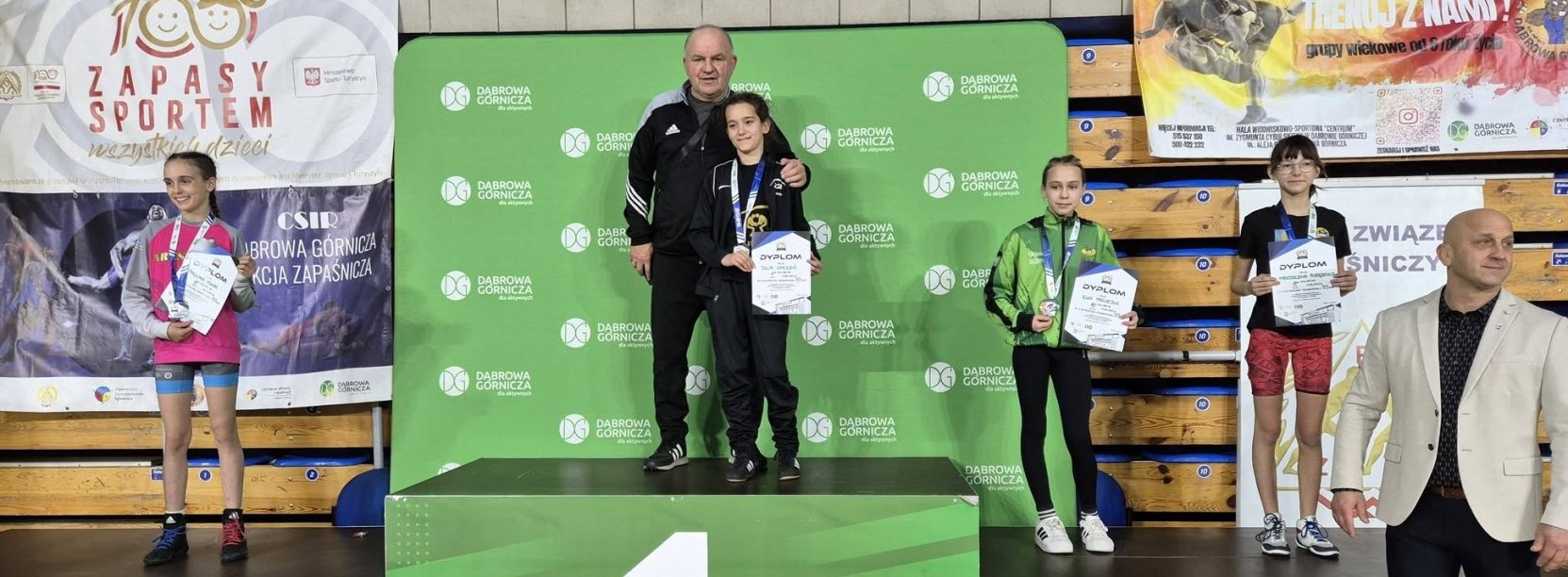 Zawodniczki stojące na zielonym podium z medalami i dyplomami