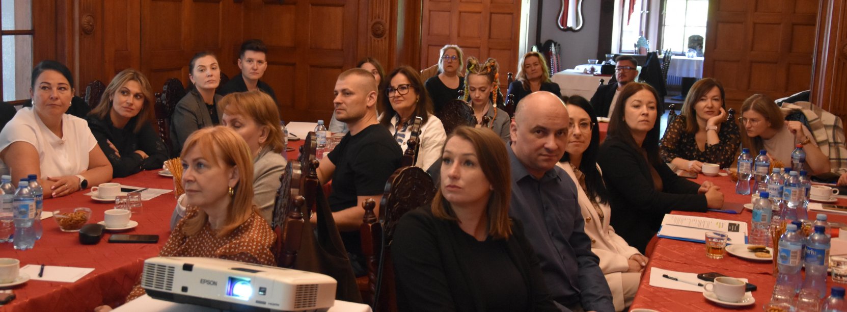 Duża grupa uczestników szkolenia siedząca przy stołach
