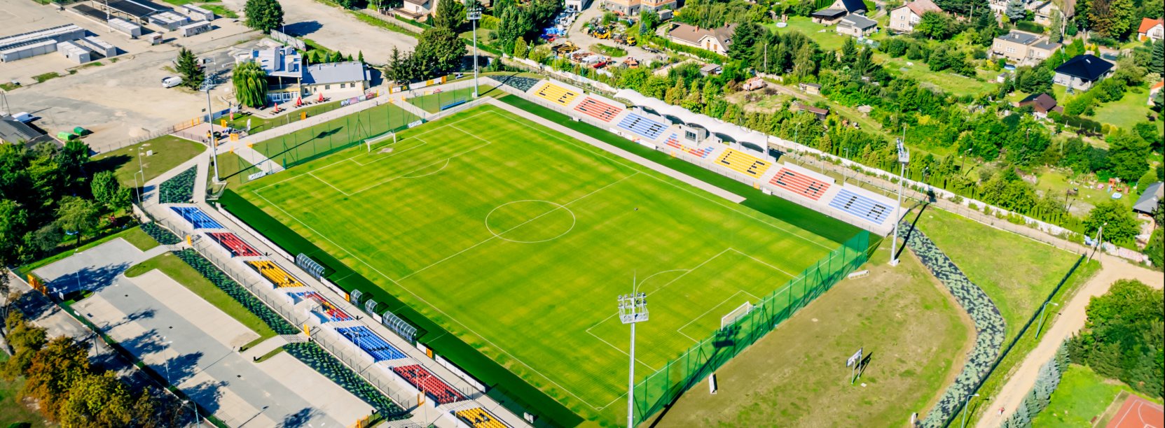 Stadion z góry, obok duży parking i plac targowy