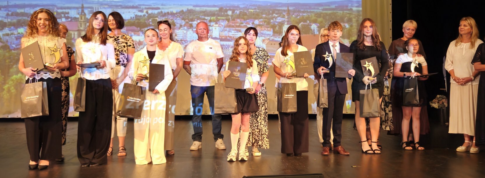 Grupa uczniów na scenie z dyplomami 