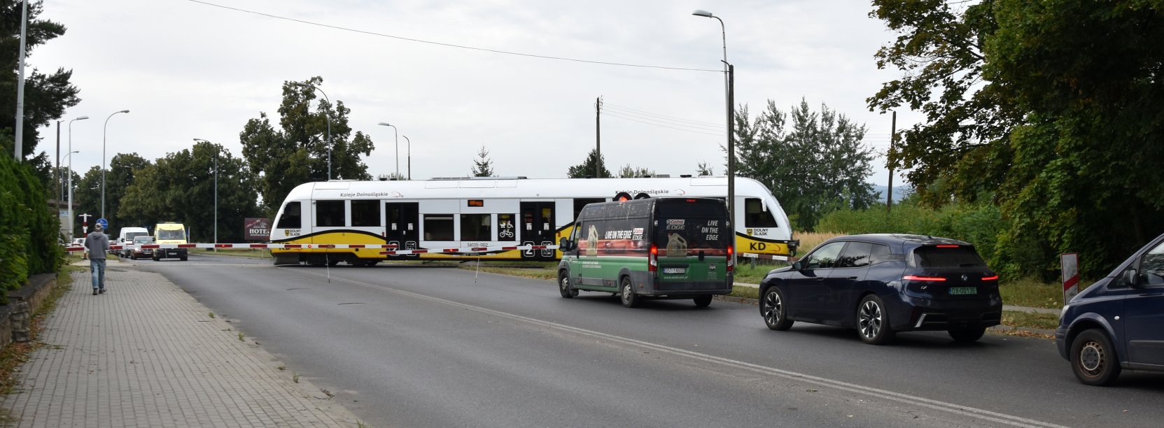 Szynobus przejeżdżający przez przejazd, przed przejazdem samochody 