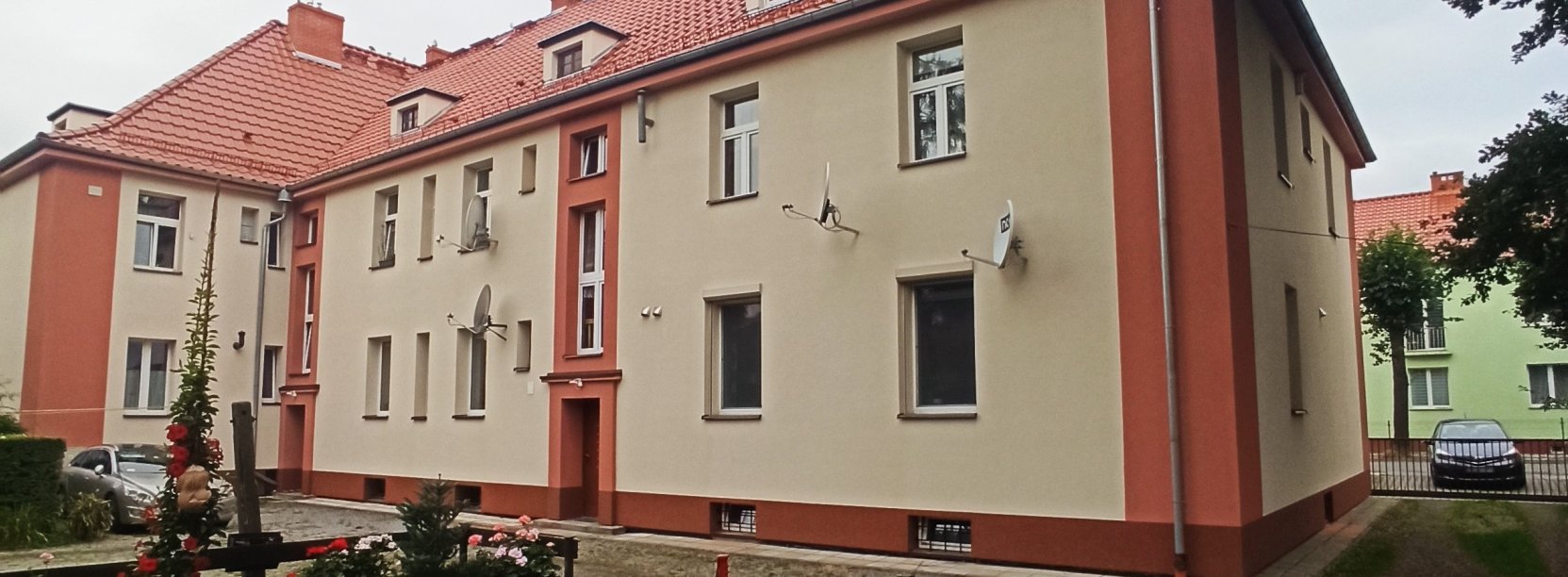 Dwupiętrowa kamienica z odnowioną elewacją w piaskowym kolorze z brązowymi elementami