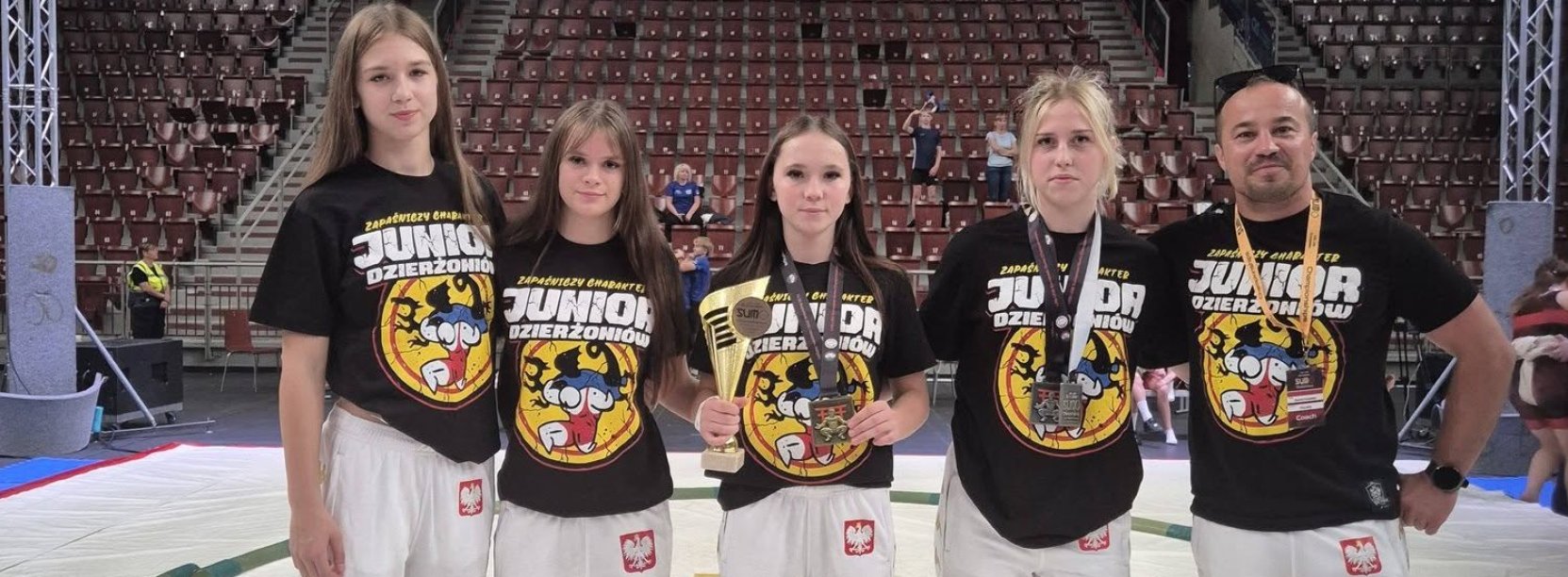 Cztery zawodniczki i trener na białej macie do walk sumo