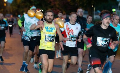 Kilkanaście osób biegnących nocą po ulicy