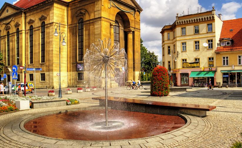 Dzierżoniowska fontanna za którą widać pomnik Jana Pawała II i kościół pw. Maryi Matki Kościoła