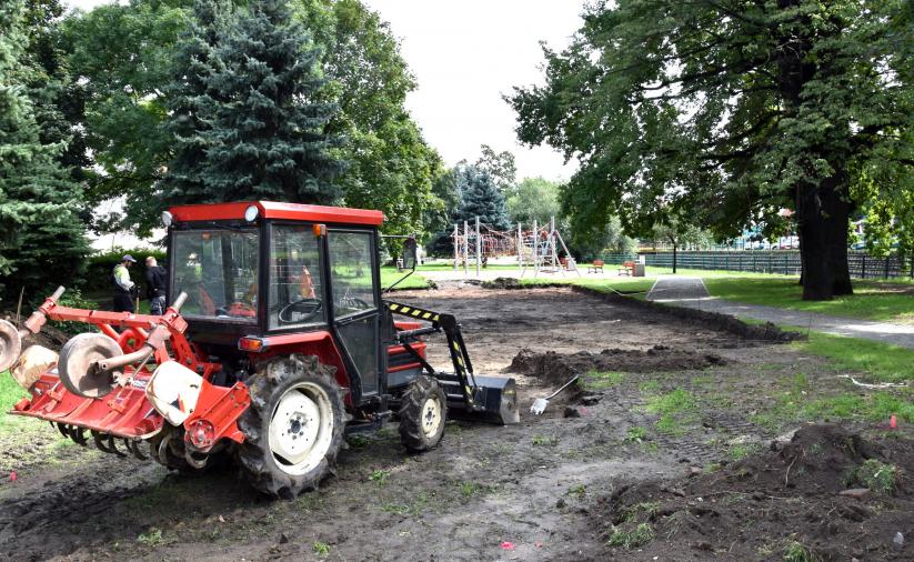 Koparka wybierająca ziemię z terenu zielonego