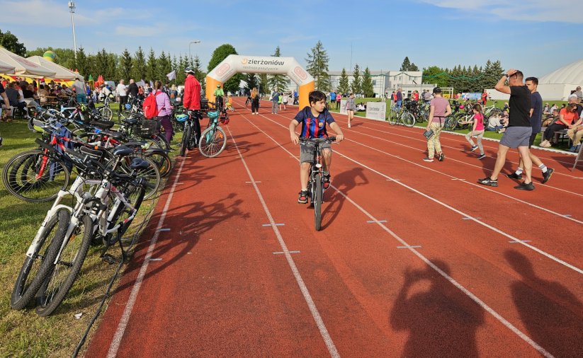 Rowerzysta jadący po czerwonej bieżni, obok kilkadziesiąt rowerów