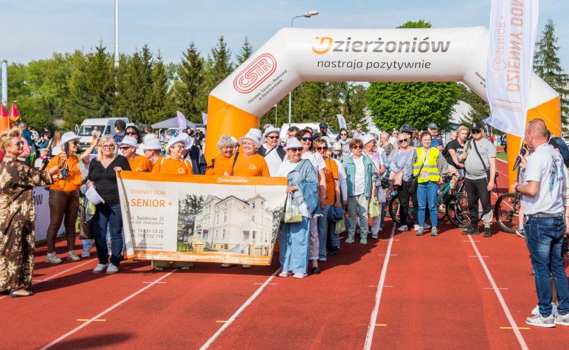 Duża grupa uśmiechniętych seniorek przy dmuchanej mecie ustawionej na bieżni
