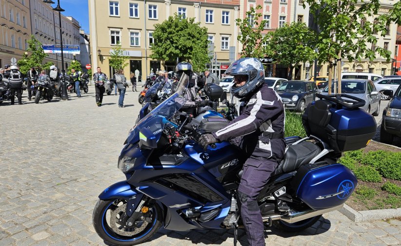 Motocyklista w kasku, za nim kilkanaście motocykli