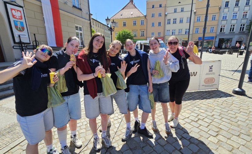 Siedem dziewczyn stojących na rynku i machających do obiektywu