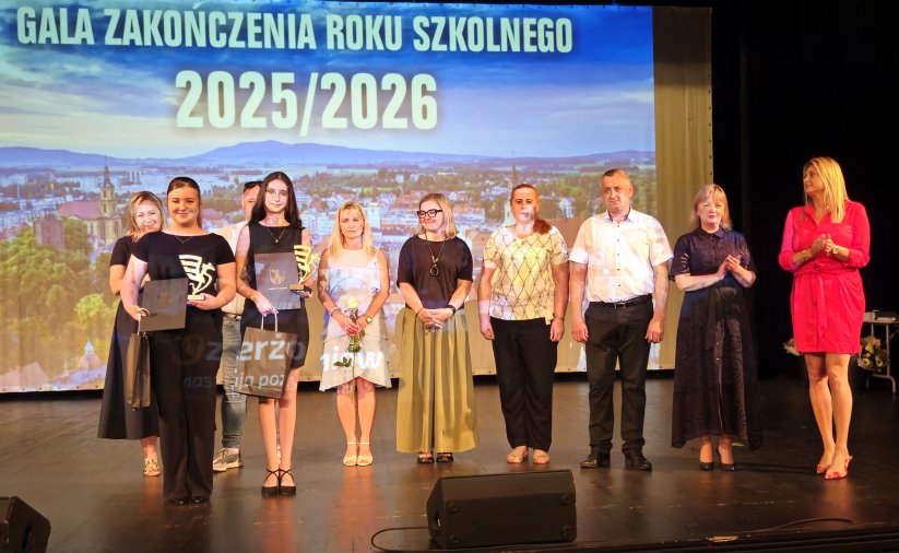 Grupa uczniów na scenie, obok nich przewodnicząca rady i zatępca burmistrza