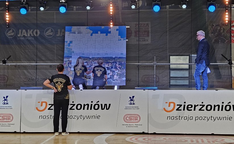 Dwie uczestniczki turnieju układające na scenie duże puzle