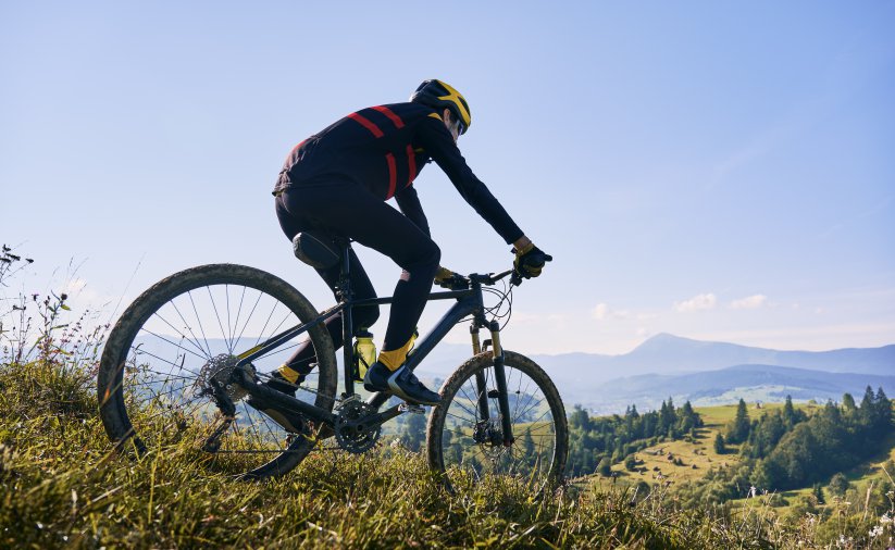 Rowerzysta w górach, zieleń i błękitne niebo