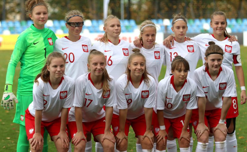 Grupowe zdjecie młodych piłkarek w narodowych strojach, w tle trybuny