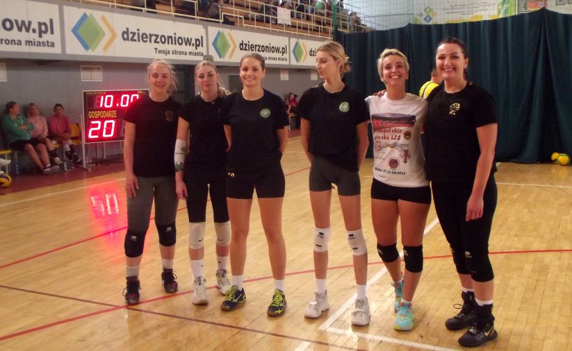 Sześć usmiechniętych siatkarek na wspólnym zdjęciu w halisportowej, w tle reklama strony www.dzierzoniow.pl