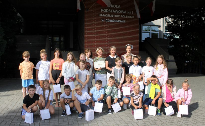 Grupowe zdjęcie uczniów i nauczycieli przed wejściem do szkoły