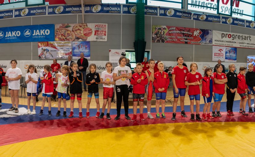Grupowe zdjęcie kilkudziesięciu zapaśników w hali sportowej