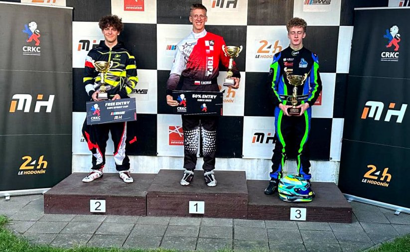 Trzech młodych kierowców w kombinezonach do ścigania na podium