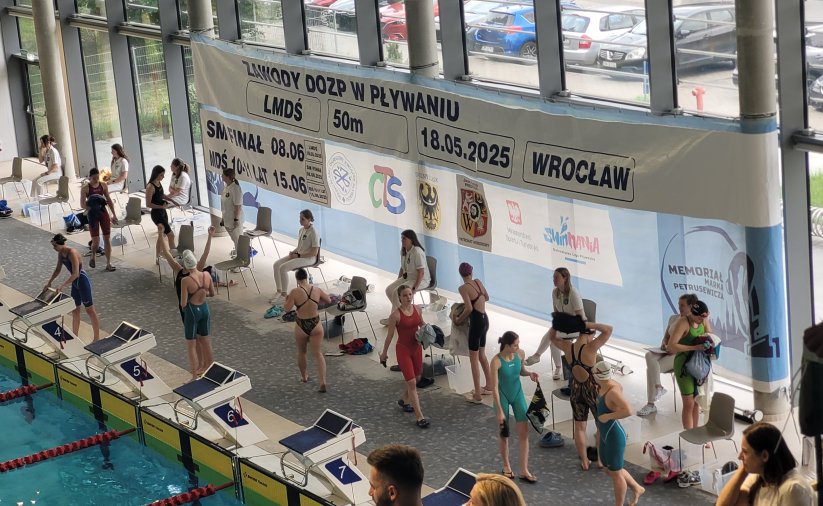 Zawodnicy przy krawędzi basenu przygotowują się do startów