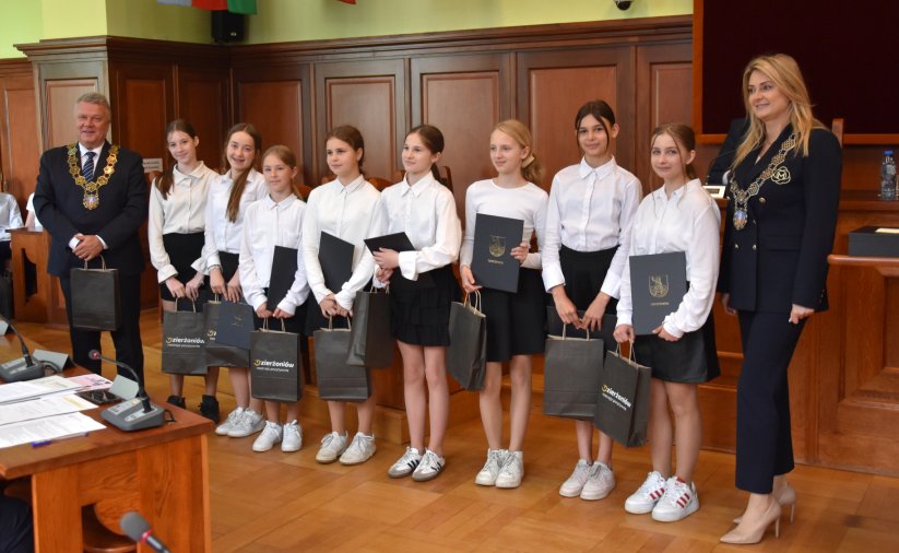 Uczennice w białych koszulach z dyplomami w rękach, obok burmsitrz i przewodnicząca Rady Miejskiej Dzierżoniowa