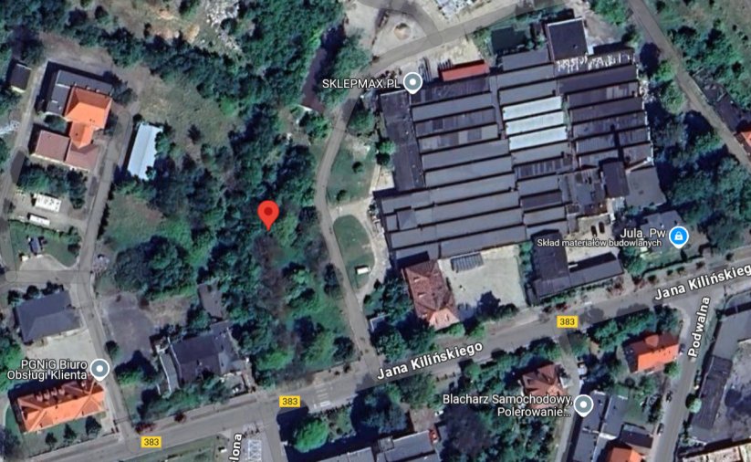 Fragment miasta z budynkami i dużą halą przmyłową z góry. Czerwonym punktem zaznaczono teren objęty przetargiem
