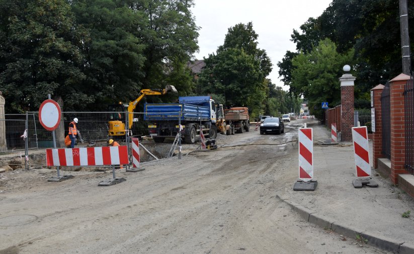 Droga miejska podczas remontu - pracująća koparka, obok samochód ciężarowy i pracownicy w pomarańczowych kamizelkach