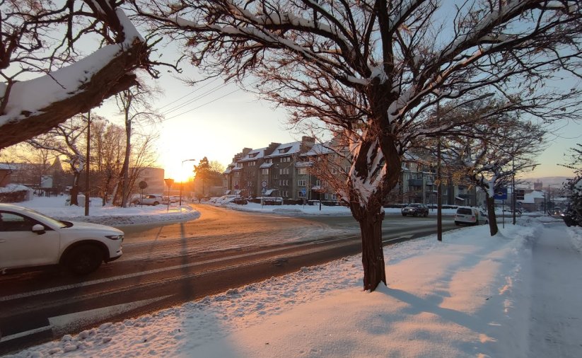 zimowa aura na ul. batalionów chłopskich, przejeżdzający biały samochód, ośnie zone chodniki i drzewa