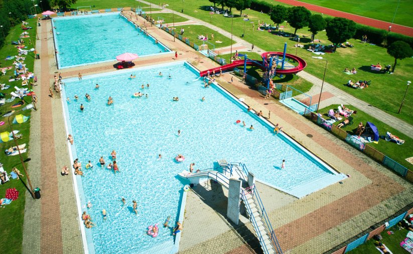 zdjęcie z lotu ptaka, dwie niecki basenowe na terenie OSiR-u, w wodzie kąpiący się ludzie