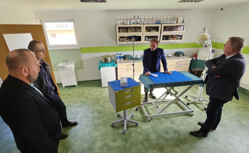 czterecvh mężczyzn w ambulatorium dla zwierząt, stoją wokół stołu zabiegowego, oglądają pomieszczenie 