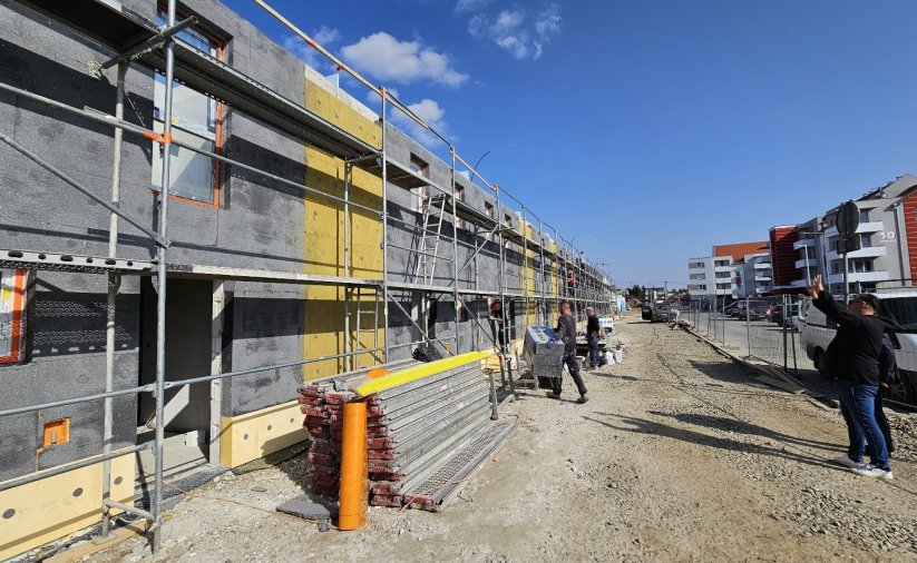 Budynek szeregowy w trakcie budowy, na drugim planie pracownicy przy rusztowaniu