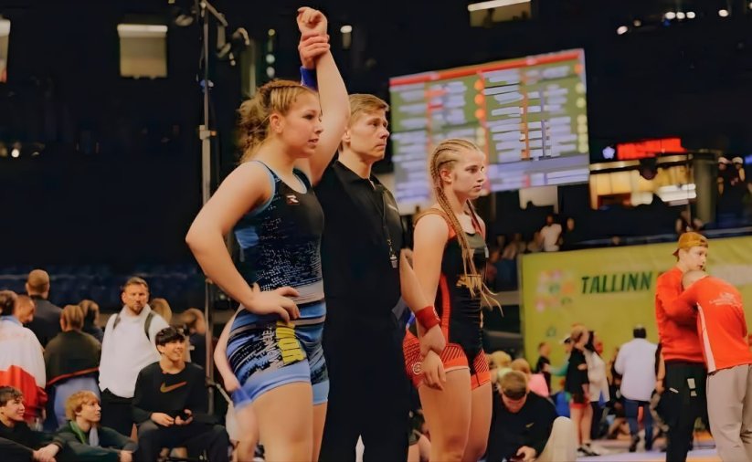 Dwie zapaśniczki, po środku sędzia unoszący rękę zwyciężczyni walki