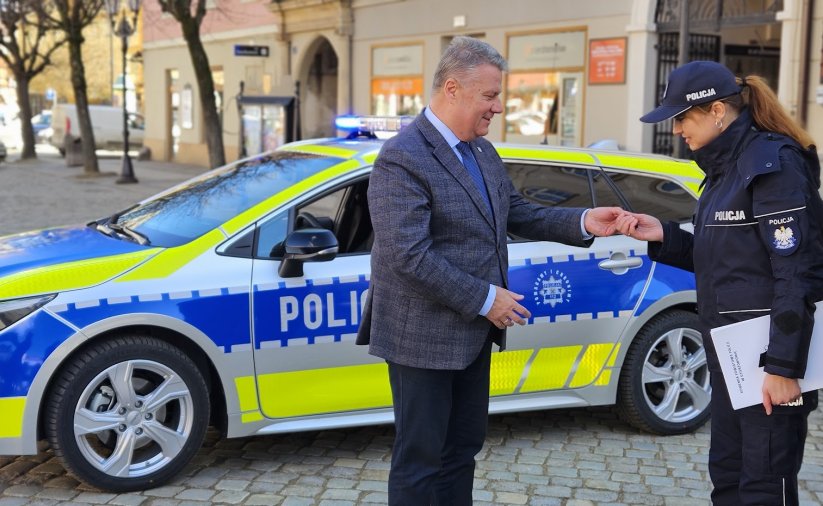 Burmistrz wręczający kluczyki policjantce, w tle nowy radiowóz