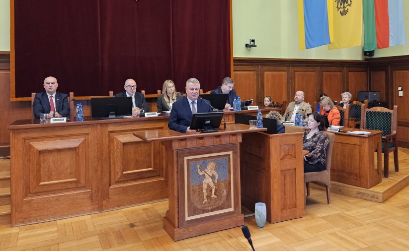 Burmistrz przy mównicy, za nim stół przy którym siedzi przewodnicząca i trzech wiceprzewodniczących