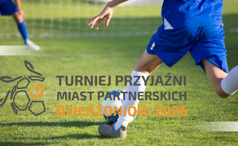 nogi piłkarza który kopie piłkę na boisku i napis turniej przyjaźni miast partnerskich