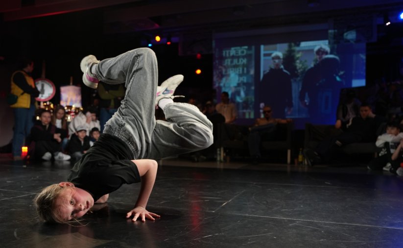 Dziewczyna tańczy będąc głową w dół, za nią widzowie