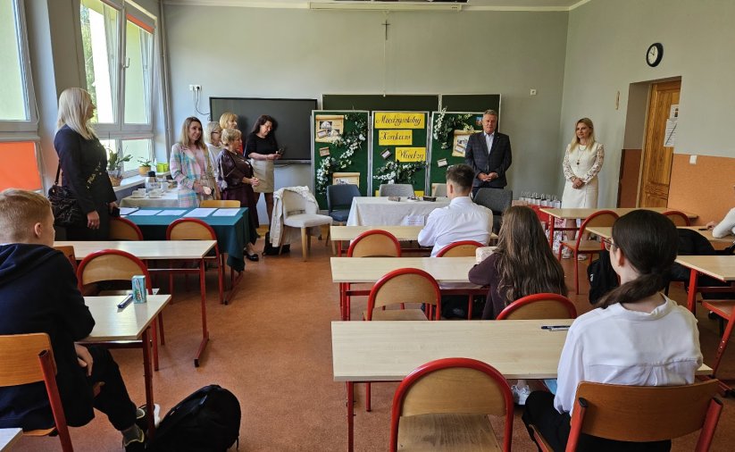 w klasie szkolenej dzieci w ławkach, widok na tablicę, przy któej pzremawia burmistrz Dzierżoniowa, obok nauczycielki