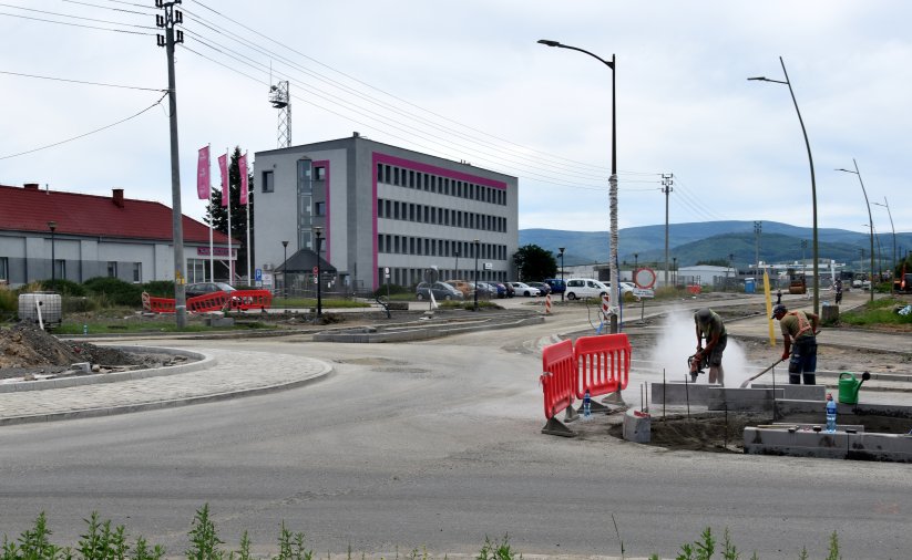Rondo i droga w budowie, przy rondzie pracownicy w tle niewielki biurowiec