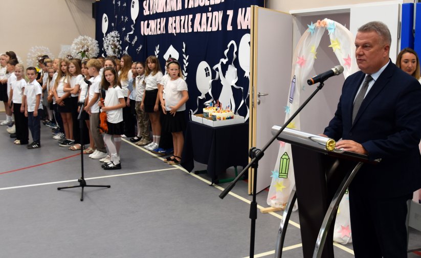 Burmistrz Dzierżoniowa przy mówinicy w sali gimnastycznej, obok grupka dzieci